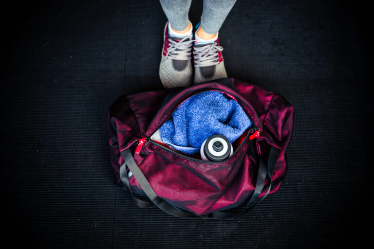 Sporttasche mit Handtuch, Trinkflasche und Laufschuhen